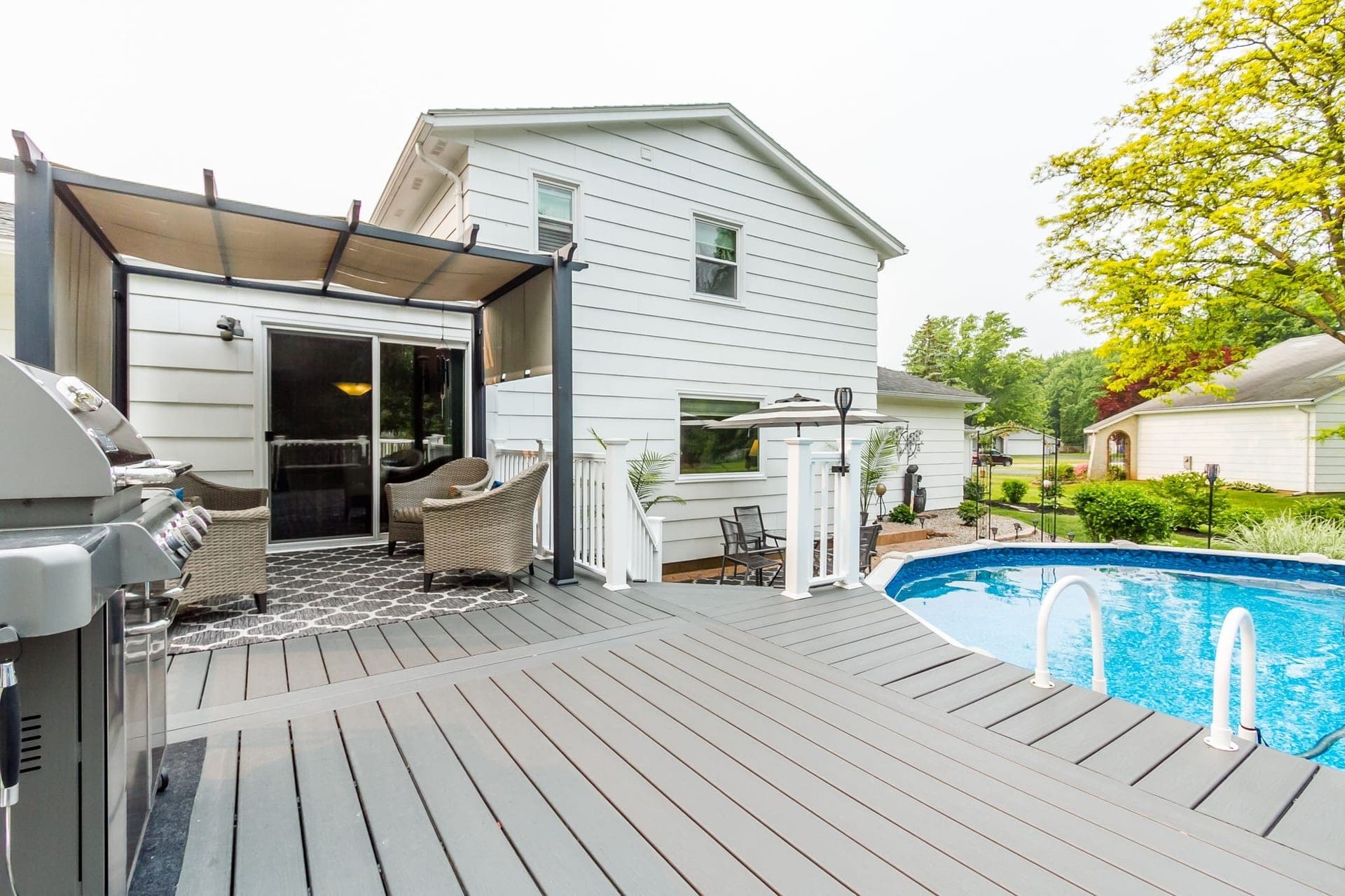 Cedar pergola attached to a brick home beside a freestanding gazebo in a sunny backyard